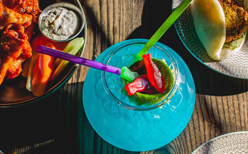Tiki-inspired drinks and steamed buns at Clever Coyote, a 90s-inspired bar, creating a nostalgic culinary experience.
